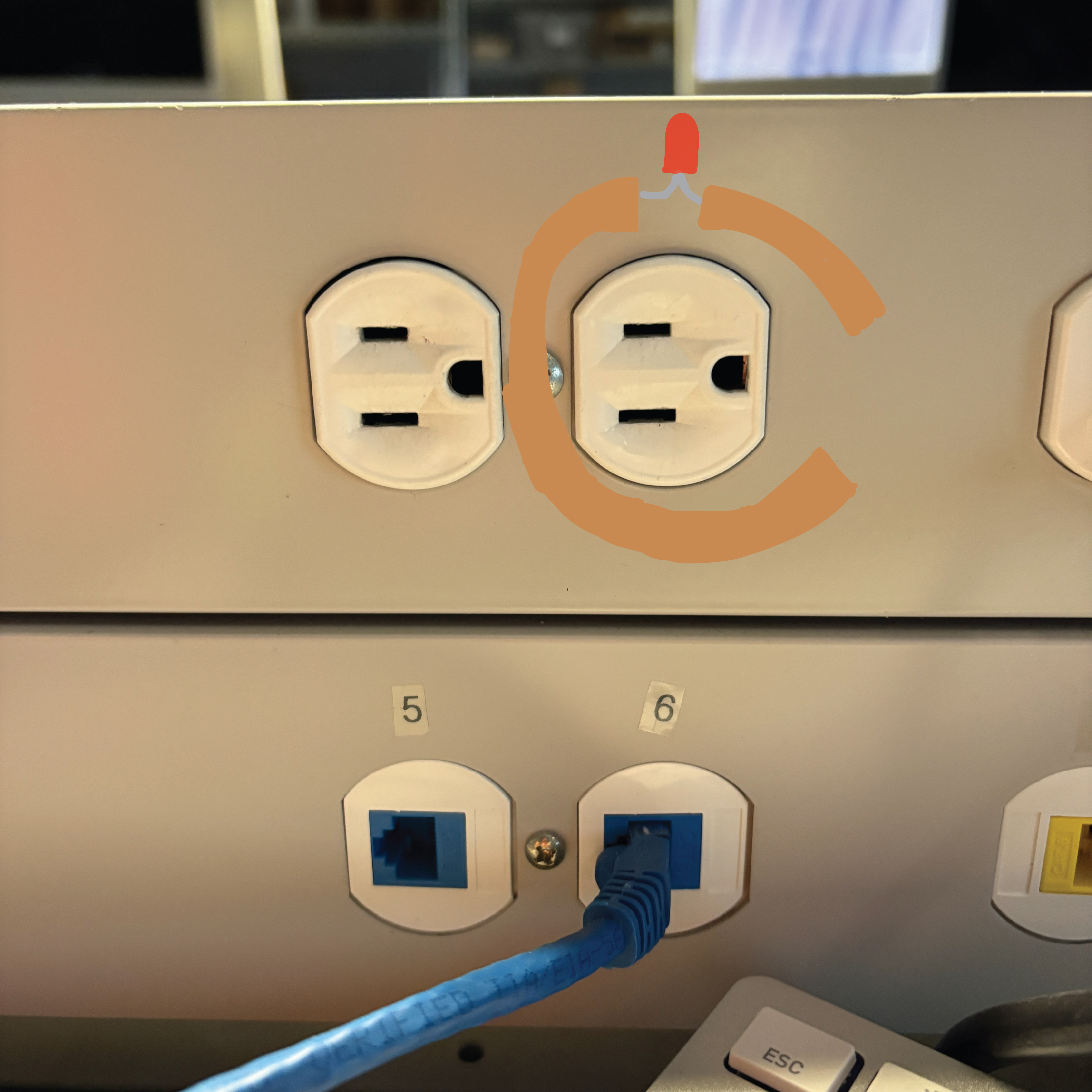 A circuit that shows a non-wearable circuit that closes as the mac charger gets plugged into the wall, causing the LED to activate as the copper tape and battery allows current to flow to the circuit on the wall.